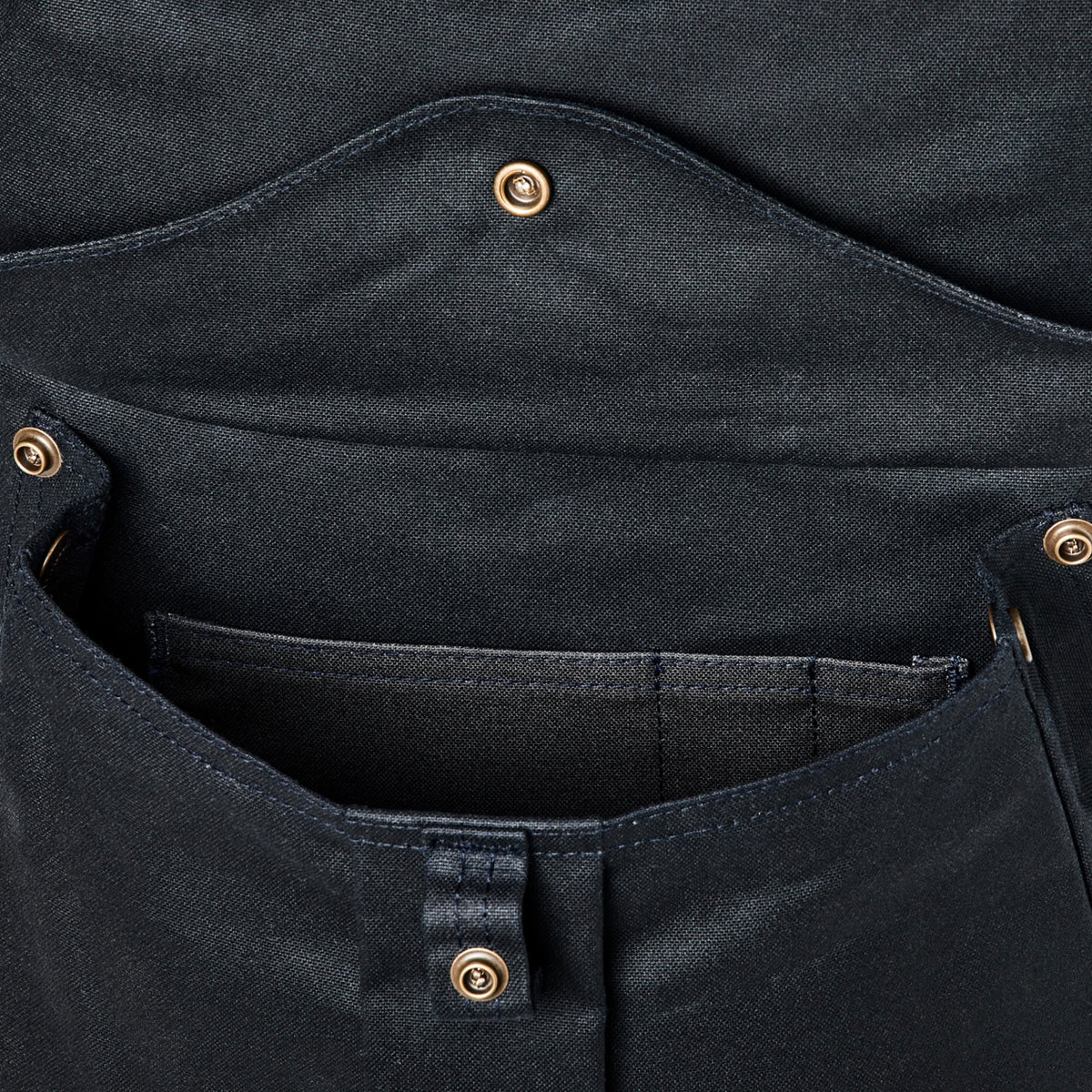 Close-up of a black pocket on backpack with button details on a white background