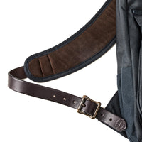 Close-up of a backpack with a brown leather strap and buckle on a white background