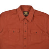 Orange shirt with two front pockets and a brand logo on the collar against a white background