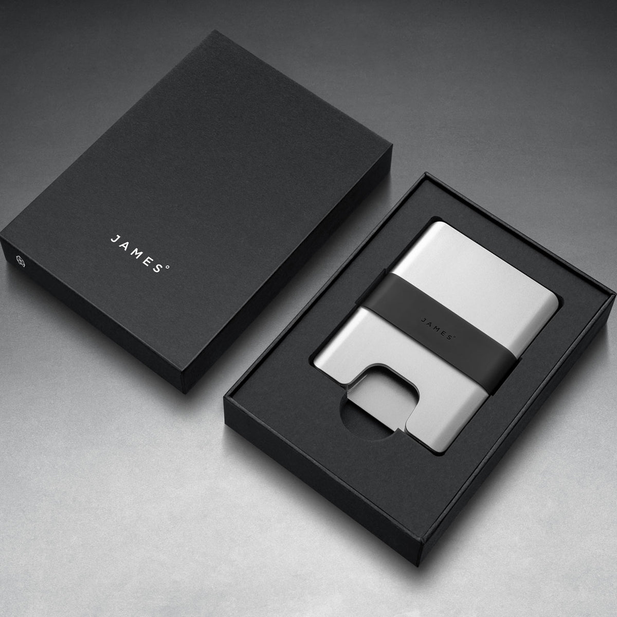 Silver wallet with black strap on a gray background