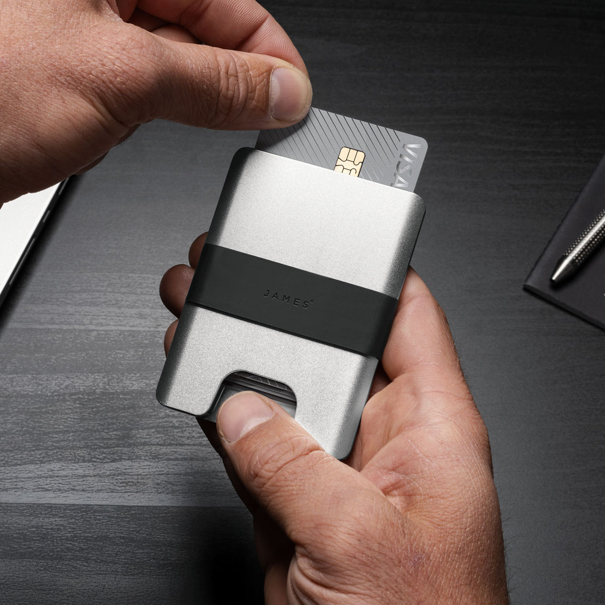 Silver wallet with black strap on a gray background