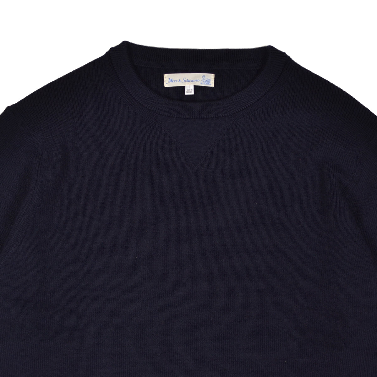 Close-up of a navy blue sweater with a brand label on a white background