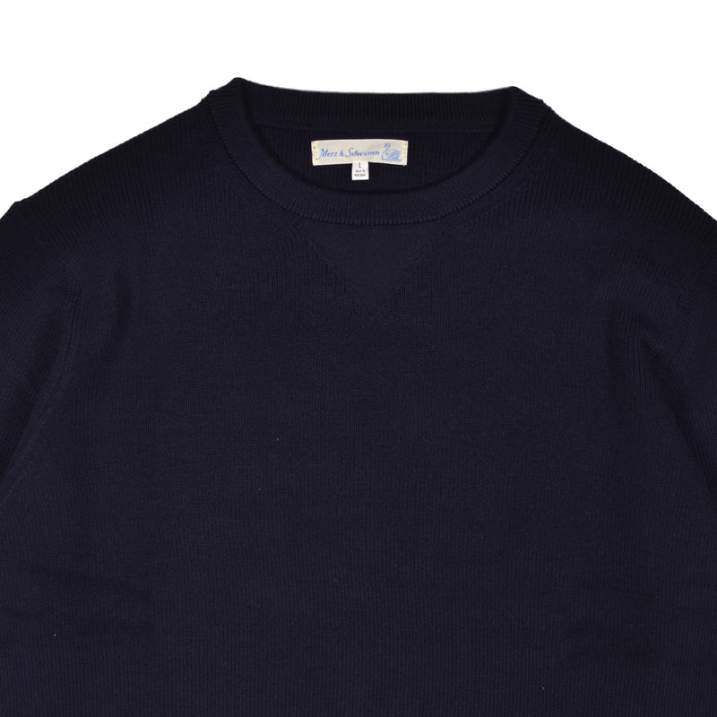 Close-up of a navy blue sweater with a brand label on a white background