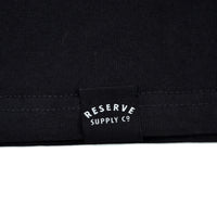 Close-up of a black fabric with 'Reserve Supply Co' logo.