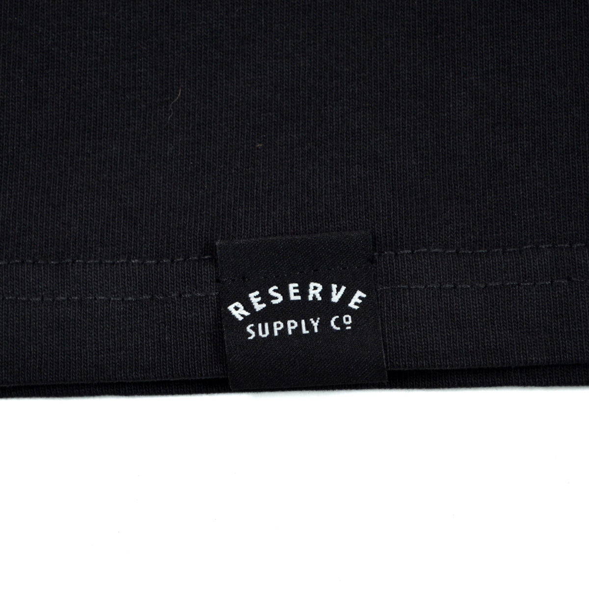 Close-up of a black fabric with 'Reserve Supply Co' logo.