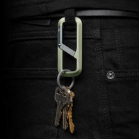 Green carabiner with keys attached to a black pants pocket