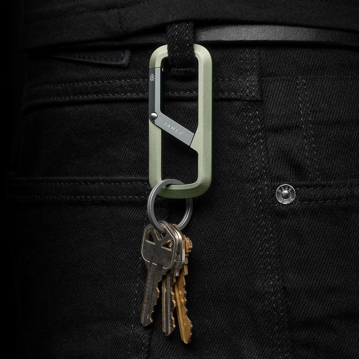 Green carabiner with keys attached to a black pants pocket