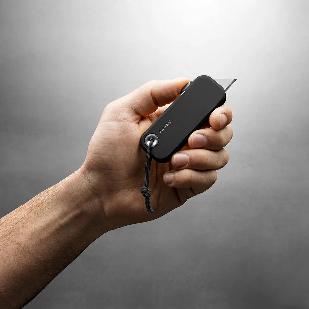 Hand holding a black multi-tool against a gray background