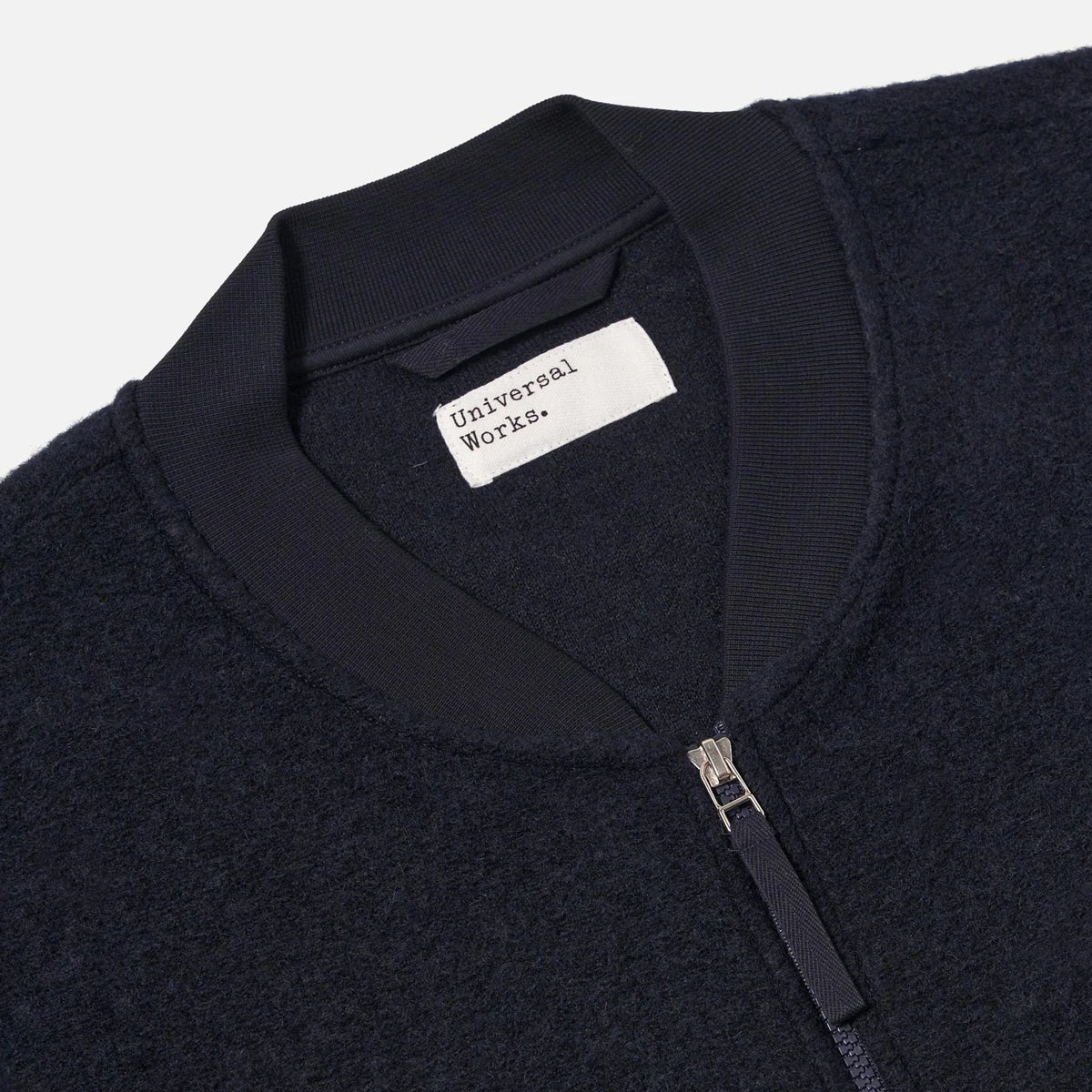 Close-up of a dark jacket with a visible brand label on a light gray background
