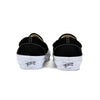 Black slip-on sneakers with white soles on a white background